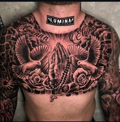 a man's chest covered in tattoos with roses and doves on the chest