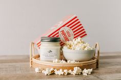 a bowl of popcorn and a jar of yogurt sit on a wooden table