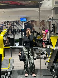 a woman taking a selfie in a gym with her cell phone up to her ear