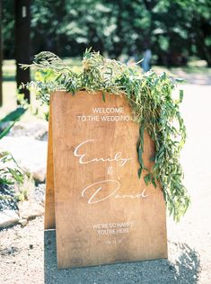 a wooden sign with greenery on it that says welcome to the wedding