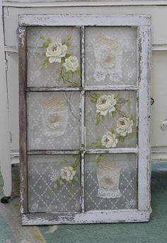 an old window is decorated with flowers and lace