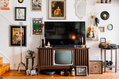 an old fashioned television sitting on top of a wooden stand in front of a staircase