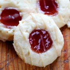 three cookies with jam on them sitting on a wooden surface