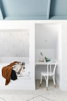 a white desk and chair in a room with blue ceiling tiles on the walls, along with an open closet