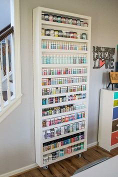 a white shelf filled with lots of different types of medicine and other medical supplies next to a window