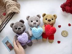 three crocheted teddy bears holding hearts in their hands