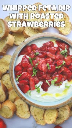 a bowl filled with strawberries sitting on top of a table next to crackers