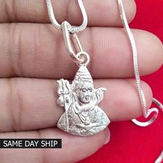 a hand holding a silver pendant with a buddha charm on it's back and the words same day shop written below