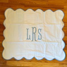 a towel with the word lrs on it sitting on a wooden floor next to a pair of scissors