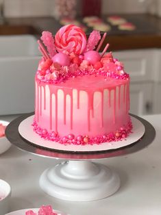 a cake with pink icing and candies on top is sitting on a table