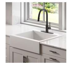 a white kitchen sink with black faucet in front of a window and windowsill