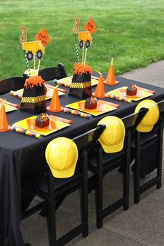 a table set up for a construction themed birthday party with cones and hats on it