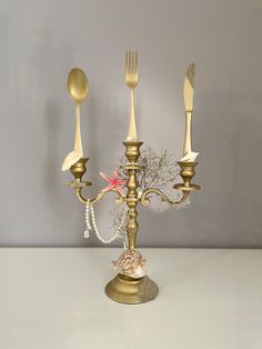 a gold candelabra with three forks and two spoons on top of it