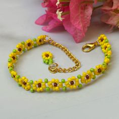 a yellow and green beaded bracelet next to pink flowers