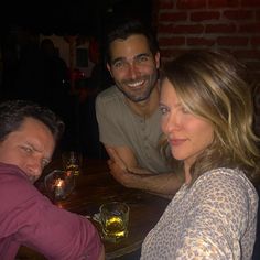 three people sitting at a table with drinks