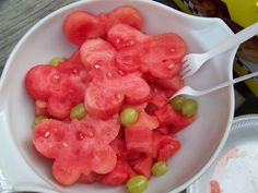 a white bowl filled with watermelon and grapes