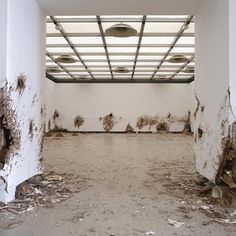 an empty room with white walls and peeling paint on the floor, in front of a ceiling light