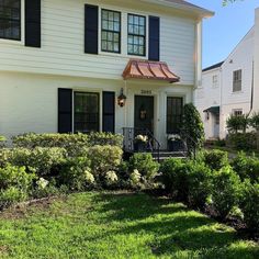 a white house with black shutters and green grass