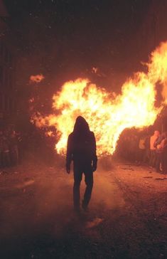 a person standing in the middle of a street with fire coming out of it and people watching