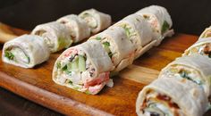 there are several rolls on the cutting board with some meat and vegetables in them, ready to be eaten