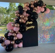 a black and gold balloon arch with happy birthday written on the front, surrounded by balloons