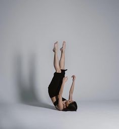 a woman is doing a handstand on the floor with her legs up in the air