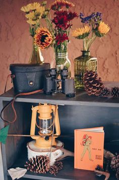 flowers and pine cones are sitting on a shelf