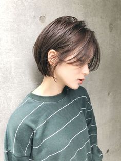 a woman with short hair standing against a wall