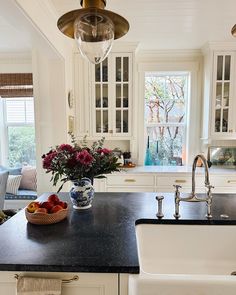 a bowl of fruit is sitting on the kitchen counter next to a sink and window