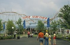 several people are standing in front of the entrance to a roller coaster at an amusement park