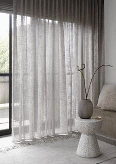 a living room filled with furniture and a window covered in sheer curtains next to a couch