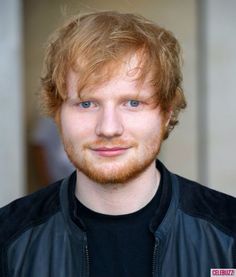 a close up of a person wearing a leather jacket and smiling at the camera with blue eyes