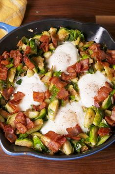 brussel sprouts with bacon and eggs in a skillet on a wooden table