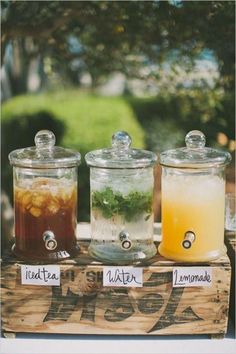 three jars filled with drinks sitting on top of a wooden crate