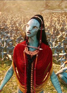 an alien woman with blue skin and long black hair standing in front of a large group of people