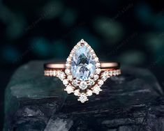 an engagement ring with a pear shaped blue topazte surrounded by smaller round diamonds