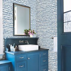 a bathroom with blue cabinets and a mirror on the wall next to a white sink