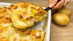 a person is cutting up some food in a white casserole dish on a wooden table