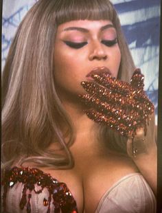 a woman with glitter on her face and hands in front of her face is holding something up to her mouth