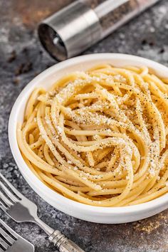 a white bowl filled with pasta and parmesan cheese on top of a table