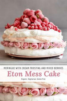 a cake with white frosting and raspberries on top, topped with pink roses