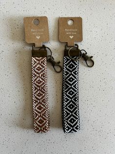 two keychains are attached to each other on a white surface with brown tags