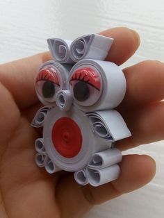 a hand holding a small plastic toy with eyes and eyelashes on it's face