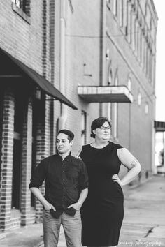 a man and woman standing next to each other in front of a building