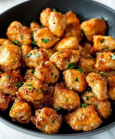 a black bowl filled with fried chicken and garnished with parsley