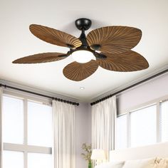 a bed room with a large white bed and a ceiling fan in the middle of it