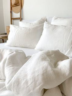 a bed with white sheets and pillows on it