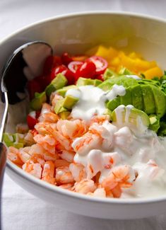 a white bowl filled with shrimp, lettuce, tomatoes and sour cream dressing