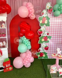 balloons and other decorations are displayed on the floor in front of a pink wall with green grass