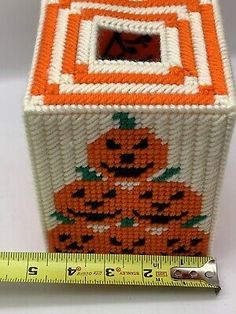 an orange and white box with pumpkins on it next to a measuring tape holder